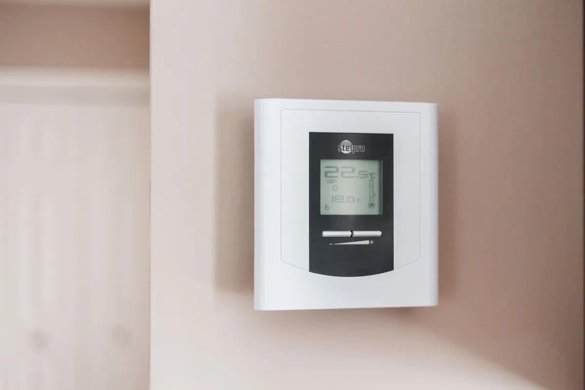 A modern digital thermostat on a wall, highlighting the importance of HVAC systems for urgent needs.
